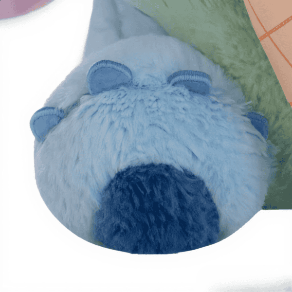 Close-up van de blauwe Stitch knuffel die een roze ijsje met chocoladesaus in zijn poot vasthoudt.