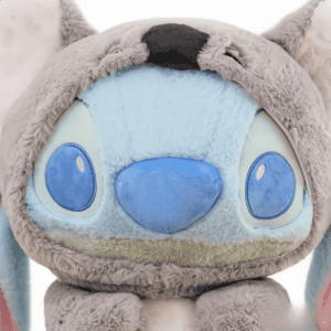 Gedetailleerde close-up van het gezicht van een blauwe pluche Stitch knuffel. Stitch heeft grote ogen, een brede glimlach en een koala-achtig uiterlijk.